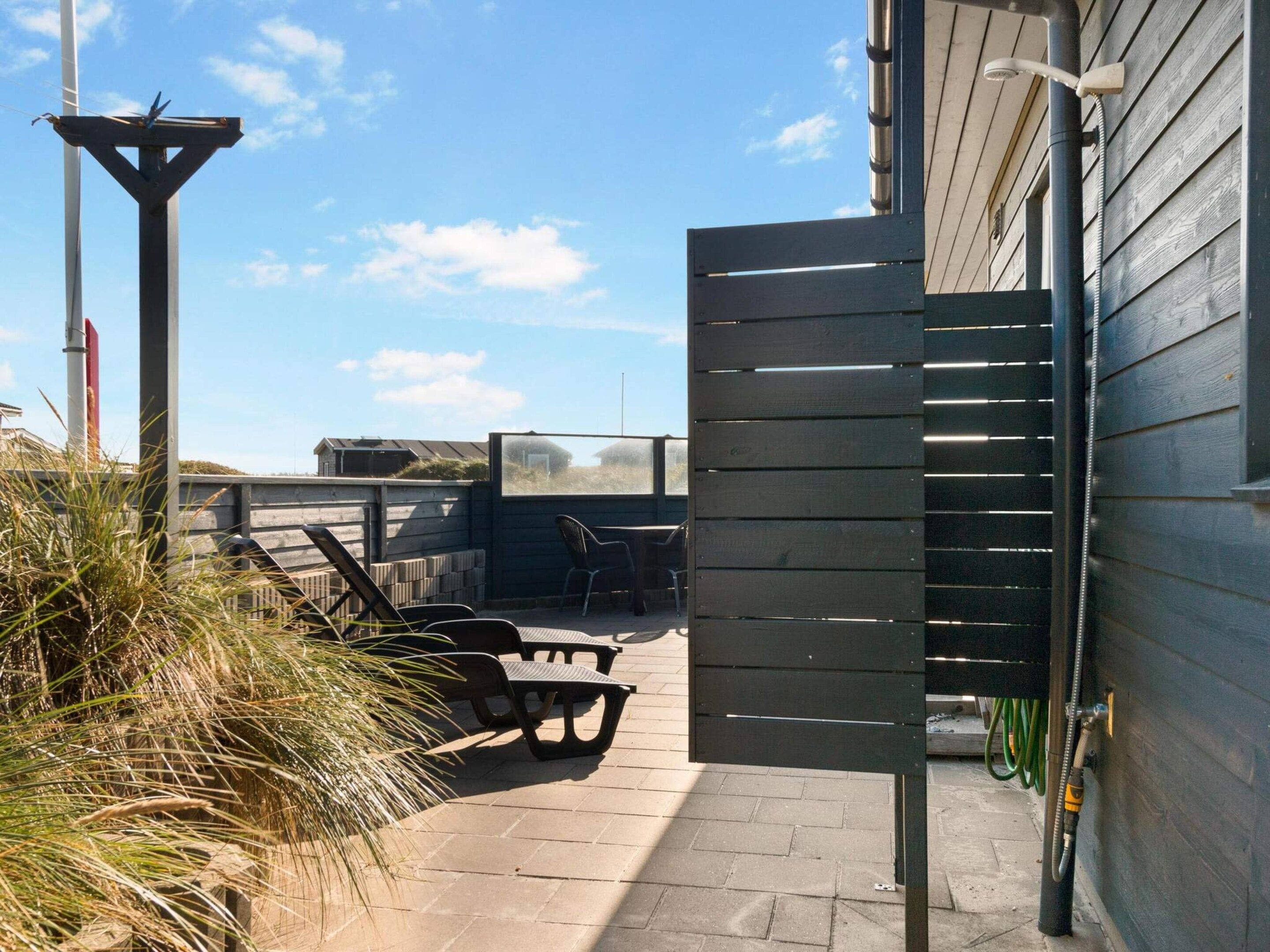 An outdoor patio area with a wooden fence, a pergola, and outdoor seating.