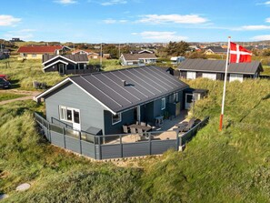 A modern house with a flat roof, a deck, and a flagpole with a flag.