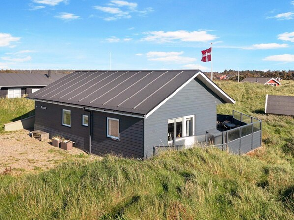 A modern house with a sloped roof, a small porch, and a flag.