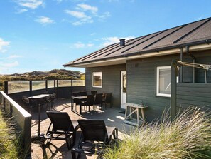 A building with a covered patio area, outdoor seating, and a view of the landscape.