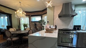 Cozinha moderna com ilha central, eletrodomésticos de aço inoxidável e um candelabro.
