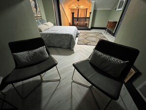 A compact bedroom with a bed, two black chairs, a patterned rug, and a small balcony with a railing. - 4 BR, Luxurious-Gem/Mansion in Heart of Denver (Denver)