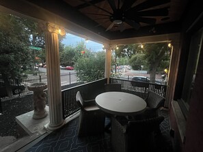 A covered outdoor seating area with a round table and chairs, a decorative stone planter, and a view of the street with cars and trees. - 4 BR, Luxurious-Gem/Mansion in Heart of Denver (Denver)