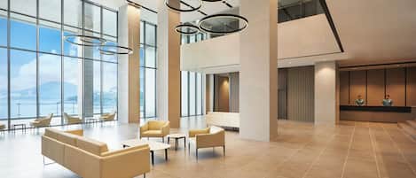 A spacious lobby with large windows, a high ceiling, and modern furniture.