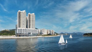 A modern high-rise hotel by the water with sailboats in the background. - YEOSU BELLE MER (Yeosu)