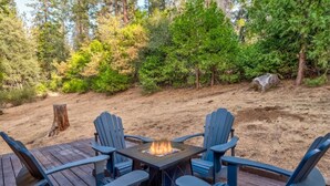 Une terrasse dotée de quatre fauteuils Adirondack et d’un foyer central.