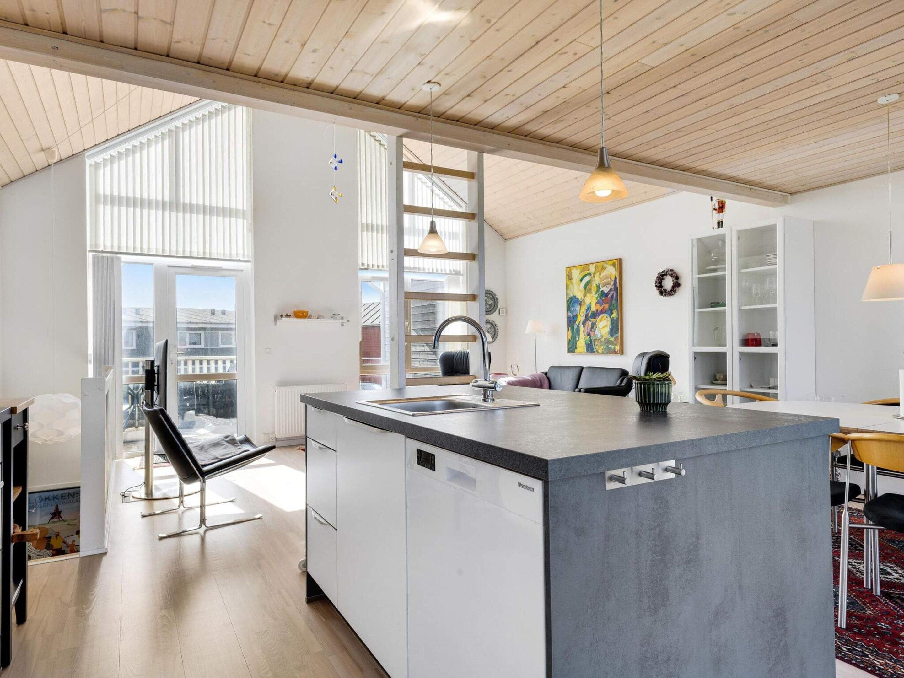 A modern kitchen with a large island, white cabinetry, and a view to the outside.