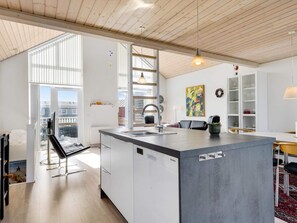 Une cuisine moderne dotée d’un grand îlot central, de meubles blancs et offrant une vue sur l’extérieur.