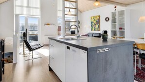 A modern kitchen with a large island, white cabinetry, and a view to the outside. - 5 Star Holiday Home in Lokken (Lokken)