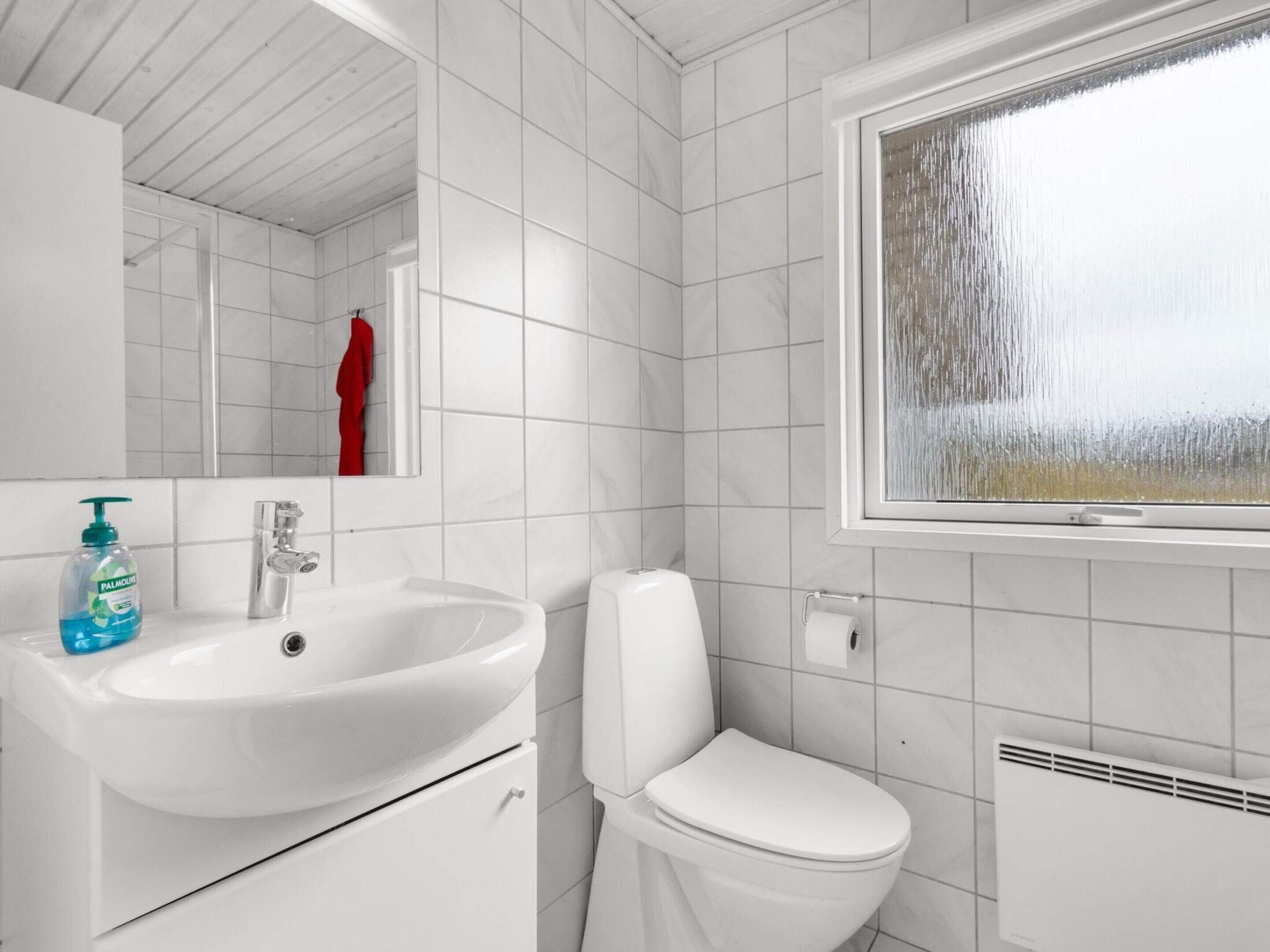 A bathroom with a white sink, toilet, and a window with frosted glass.