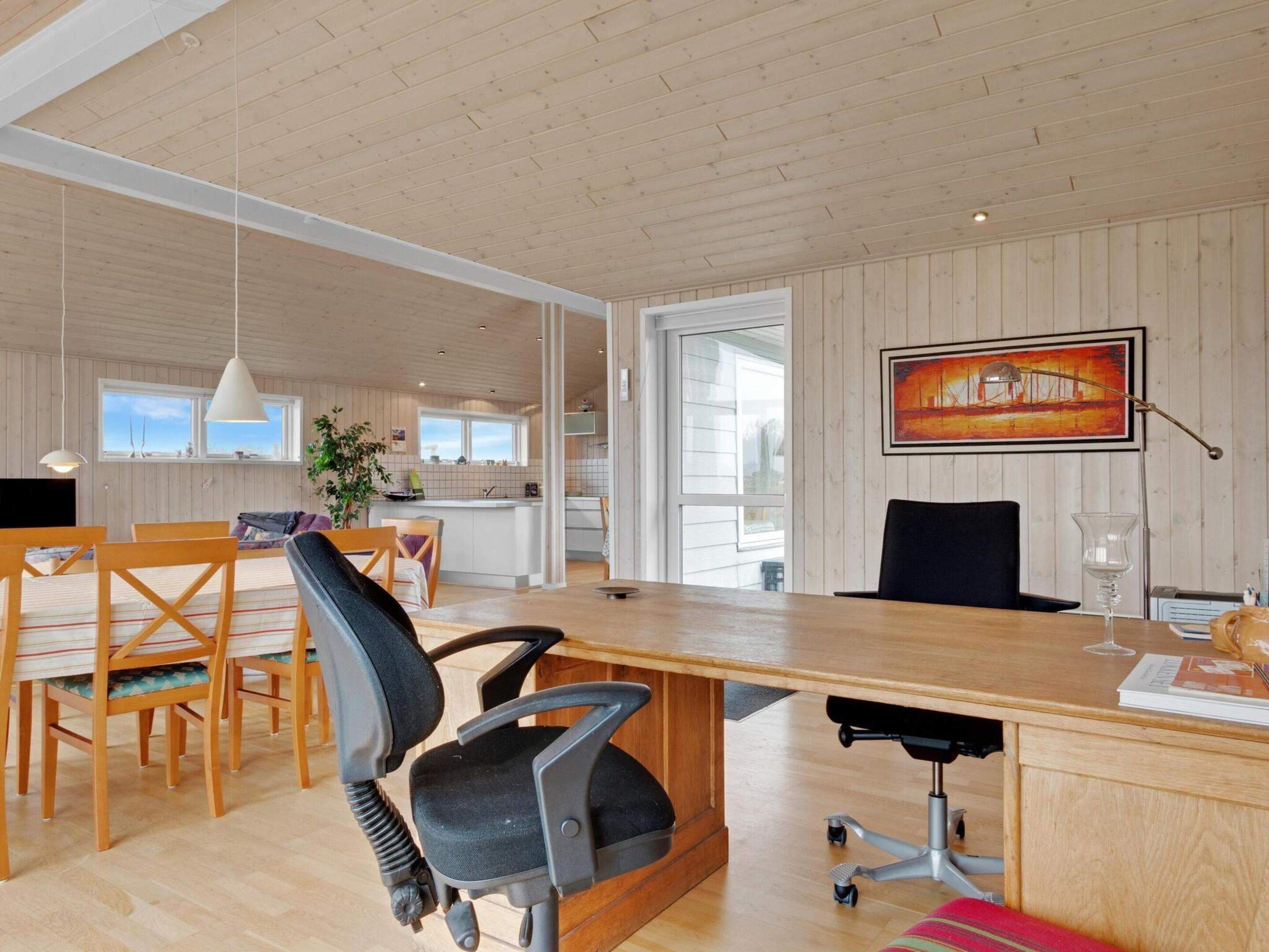 A modern kitchen with wooden cabinets, a dining area with a wooden table and chairs, and a large window providing natural light.