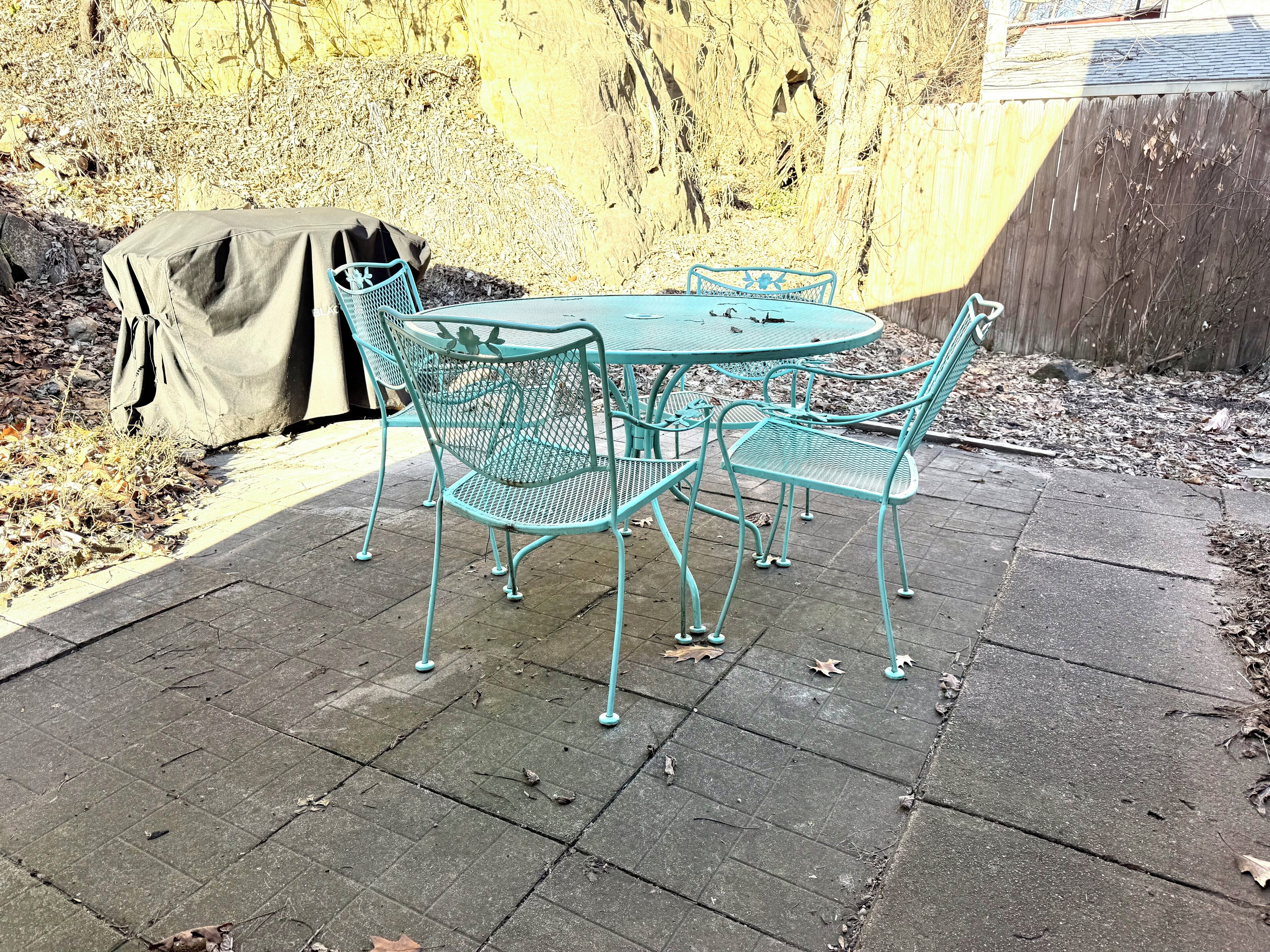Eine Terrasse mit einem runden Tisch und vier Stühlen.