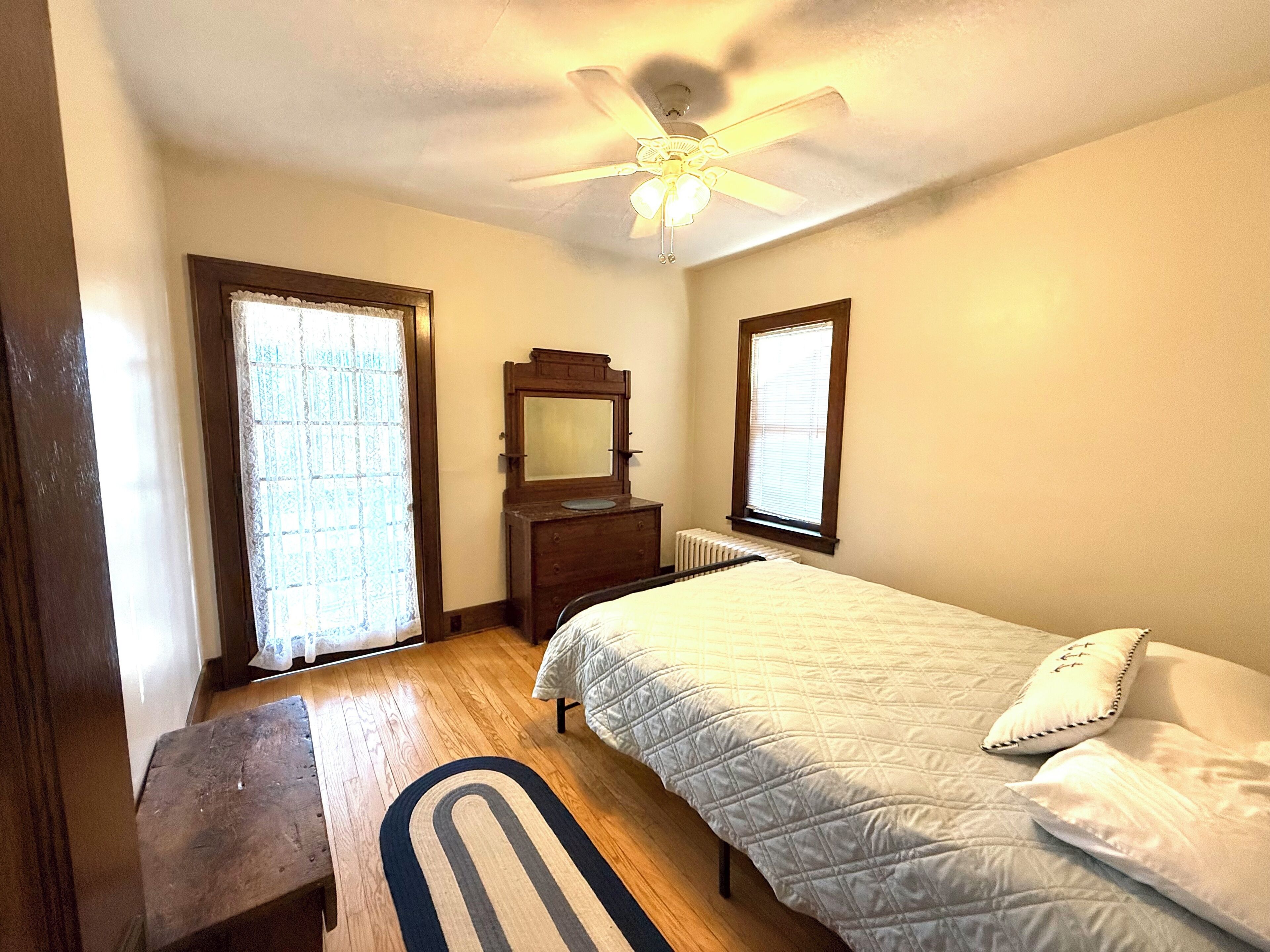 A bedroom with a bed, a dresser, a mirror, and a ceiling fan.