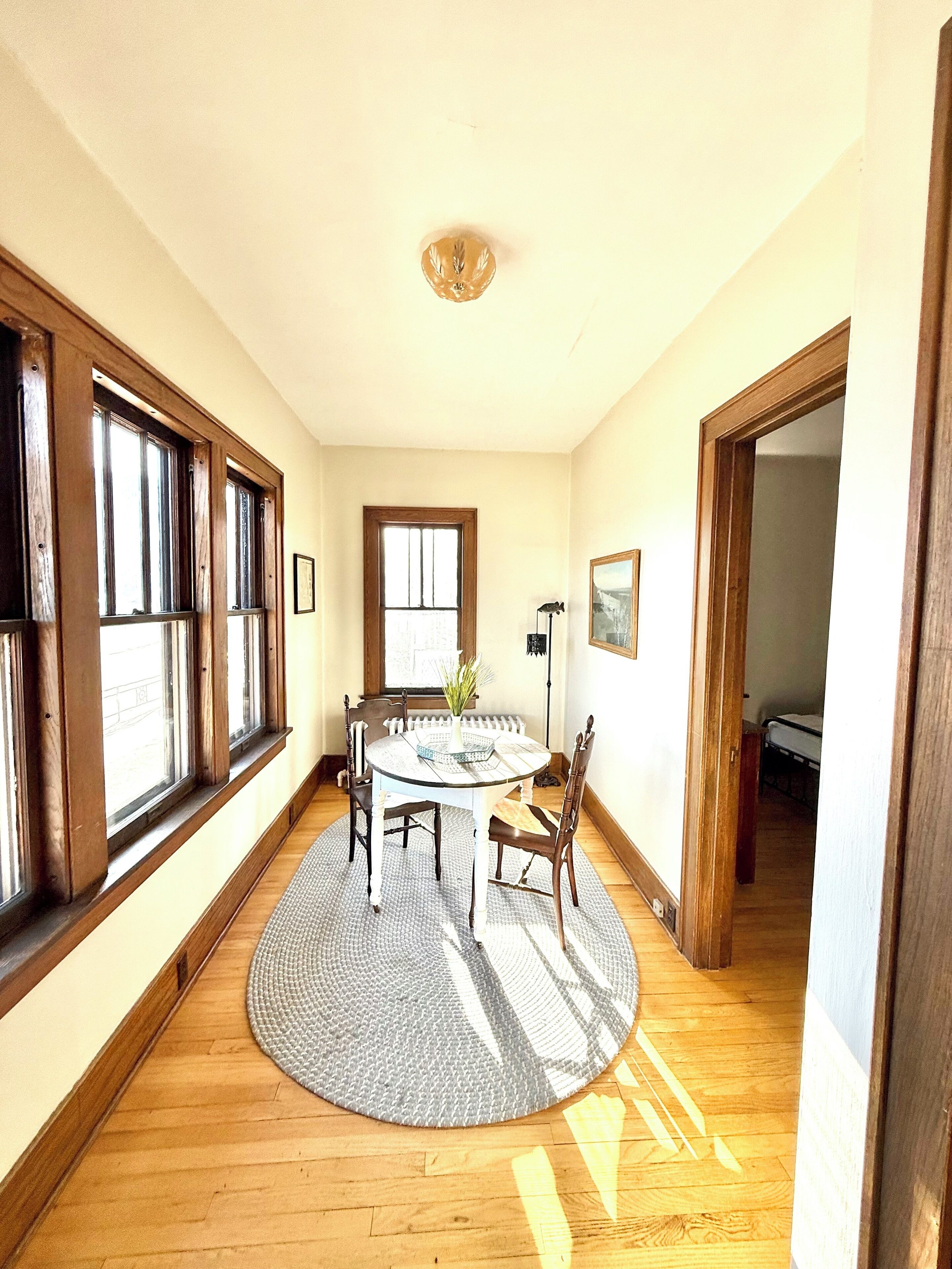 Una habitación amplia con una mesa redonda, piso de madera, ventanas grandes y vistas al exterior.