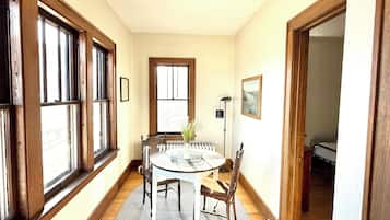 Una habitación amplia con una mesa redonda, piso de madera, ventanas grandes y vistas al exterior.