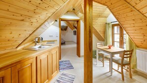 Un interior de madera con una zona de cocina, una mesa de comedor y una escalera que sube a un nivel superior.