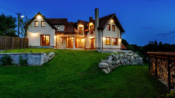 Una casa grande y moderna con césped cuidado y muros de piedra.