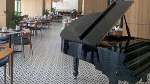 A spacious hotel lobby with a grand piano, modern decor, and a patterned floor. - Ruby Provided Arena Cam Ranh (Bac Cam Ranh)