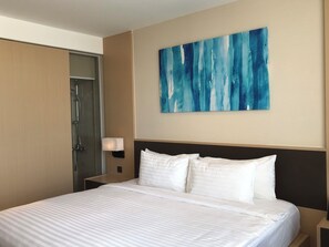 A hotel room with a bed, a nightstand, a wall-mounted lamp, and a large abstract painting. - Ruby Provided Arena Cam Ranh (Bac Cam Ranh)