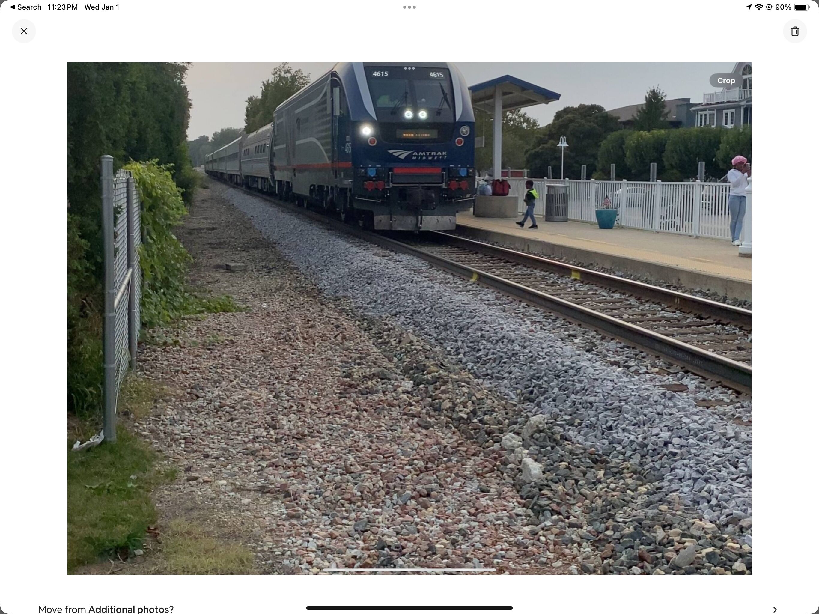 A train on tracks with a platform and a fence.