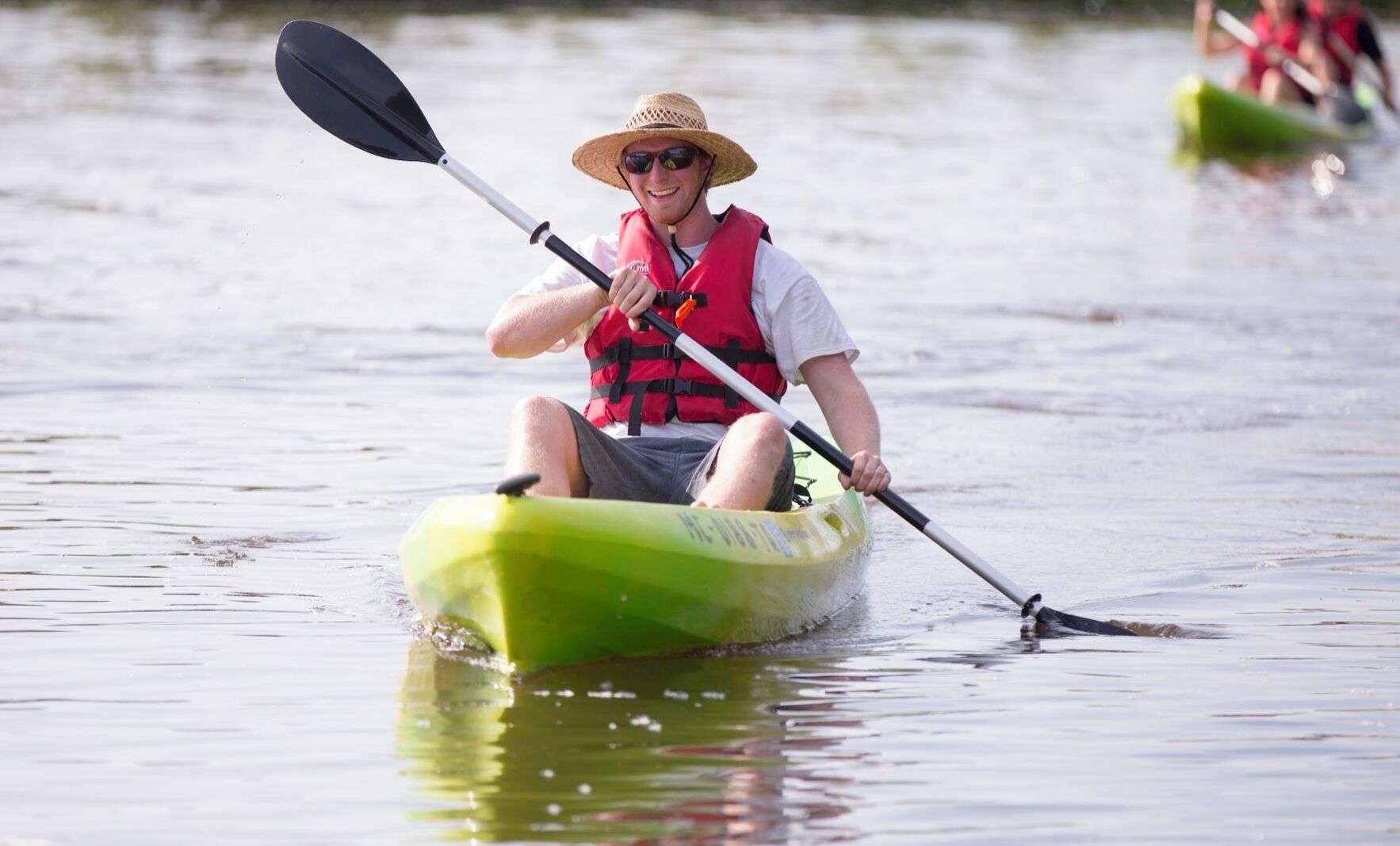 A person kayaking on a calm body of water.