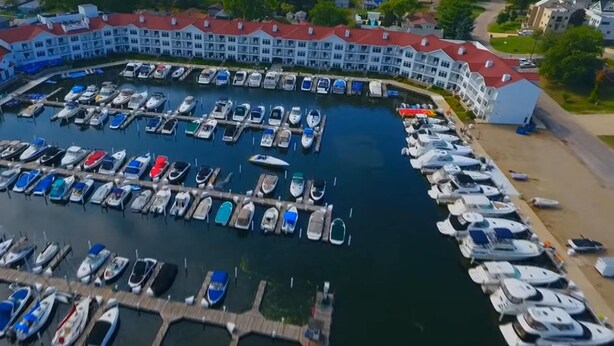 An aerial view of a marina with numerous boats docked, surrounded by buildings with red roofs.