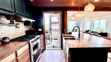 Een moderne keuken met houten kastjes, een groot eiland en uitzicht op de omgeving.