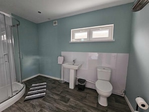 A bathroom with a shower, sink, toilet, and a small window. - Cosy Apartment that sleeps 3, Pets Welcome (Garve)