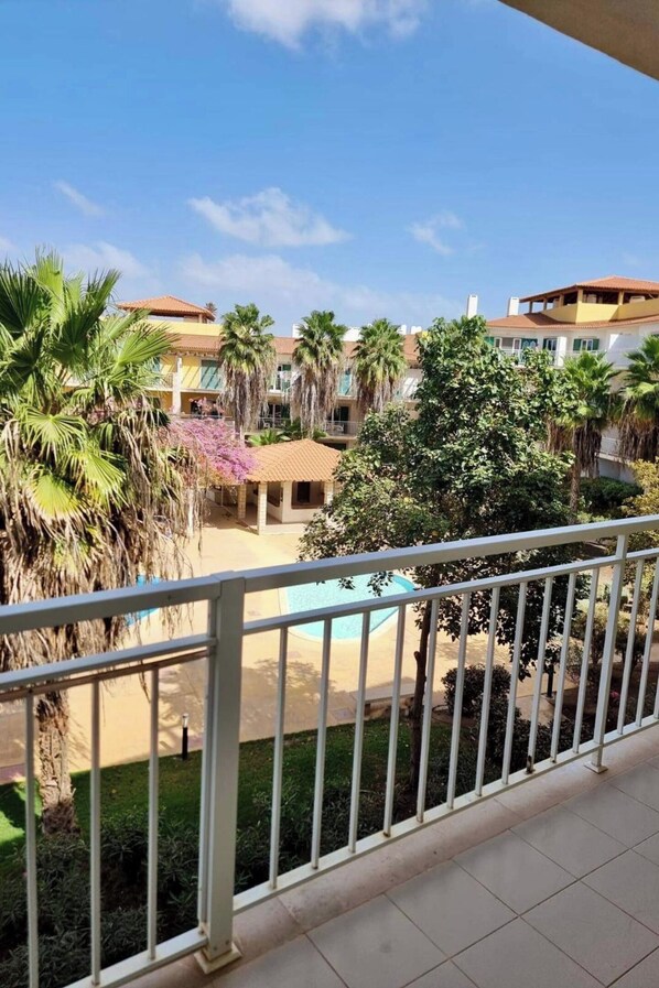 Ein Hotelinnenhof mit Pool, Palmen und einer überdachten Sitzgelegenheit.