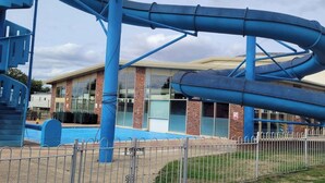 Un parc aquatique avec plusieurs toboggans et un bâtiment en arrière-plan.