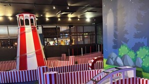 Un espace de jeux avec des barrières rayées, un petit pont et un toboggan.