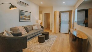 Uma sala de estar moderna com um sofá, duas mesas laterais, um tapete e um espelho grande.