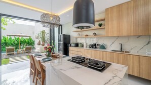 Una cocina moderna con encimera de mármol, armarios de madera y una isla central con estufa a gas.