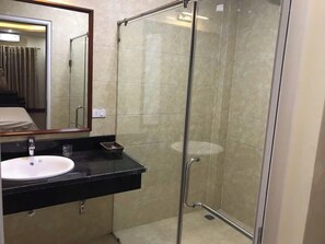 Bathroom features a glass-enclosed shower, a sink with a faucet and soap dispenser, and a mirror above.