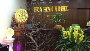 En receptionsdisk med en skylt där det står ”Hoa Binh Hotel” och klockor som visar tiden i New York, Hanoi, Peking och Tokyo.