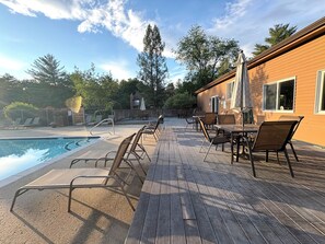 A wooden deck with lounge chairs and a pool.