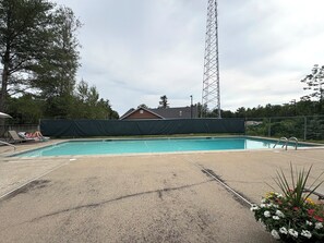 A swimming pool with a covered deck, a tall metal structure in the background, and a house. - Lincoln/White Mnt 2Br/2Ba-King bed-A/C-Pool-Monthly rental (Lincoln)