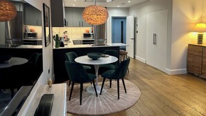 Una cucina moderna con zona pranzo, che include un tavolo rotondo con sedie, un'isola della cucina e una lampada a sospensione.