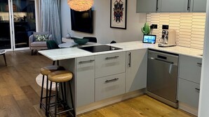 Ett modernt kök med grå skåp, en inbyggd diskmaskin och ett trägolv.