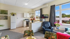 Un espacio habitable compacto con kitchenette, comedor y zona de estar con vistas al exterior.