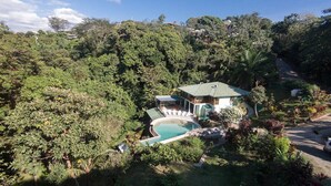 Une maison avec une piscine, entourée d’une végétation luxuriante.