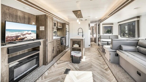 Ein kompaktes Wohnmobil-Interieur mit einer Küchenzeile, einer Sitzecke und einem Fernseher.