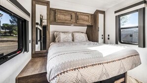 Ein Schlafzimmer mit einem Bett, einem hölzernen Kopfteil und einem Fenster.