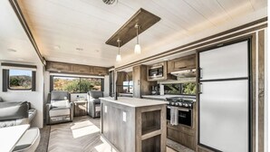 Ein modernes Wohnmobil-Interieur mit einer Küche, einer Sitzecke und einem großen Fenster mit Blick ins Freie.