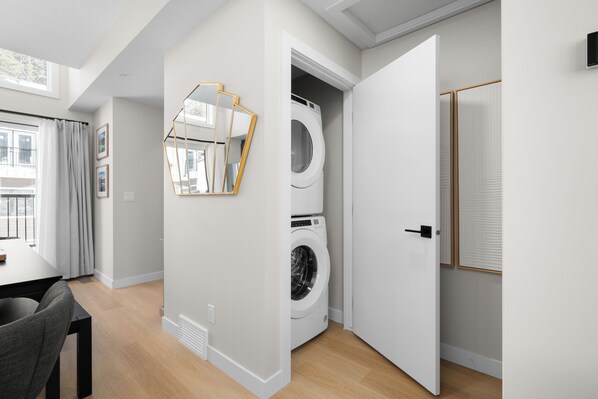 Un apartamento moderno con comedor, lavadora y un espejo grande.