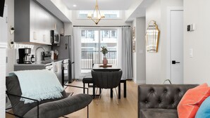 A modern kitchen with a built-in oven, a dining area with a table and chairs, and a living room with a sofa and a coffee table.