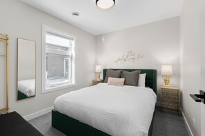 A neatly arranged bedroom with a large bed, a window, a mirror, and two bedside lamps. - Luxuriously Cozy 3-bedroom Townhouse in Harvey Heights - 2 min to Banff Gate (Harvie Heights)