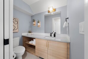 A modern bathroom with a white toilet, wooden cabinets, a white sink, and a mirror. - Luxuriously Cozy 3-bedroom Townhouse in Harvey Heights - 2 min to Banff Gate (Harvie Heights)
