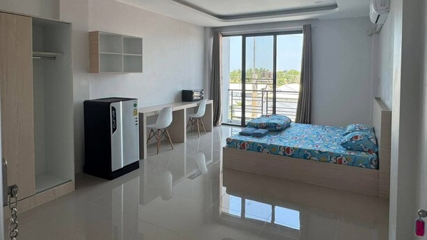 A modern room with a bed, a desk, and a chair, a small refrigerator, and a window with a view. - Langmoresort (Ongkharak)