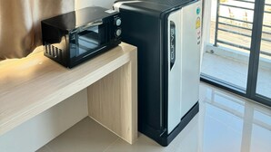 A compact kitchenette with a microwave, a mini-fridge, and a built-in shelf unit. - Langmoresort (Ongkharak)